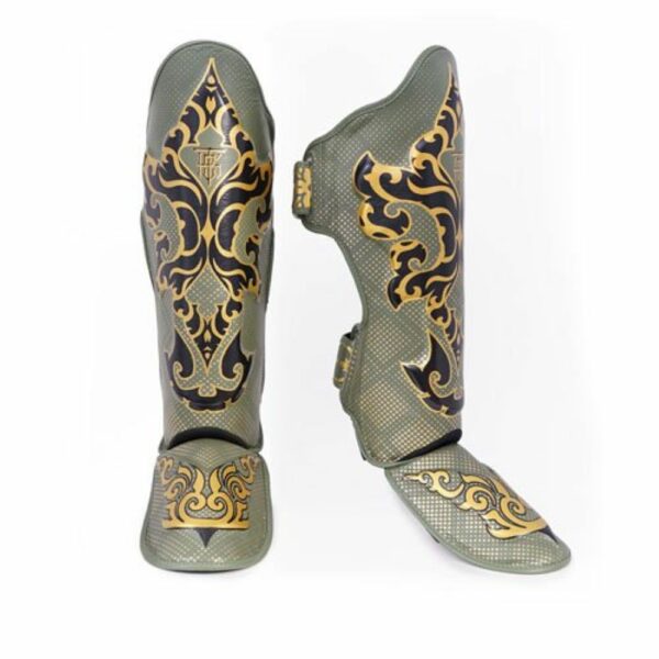Paire de protège-tibias TopKing modèle Kanok, khaki avec motifs dorés inspirés de l’art traditionnel thaïlandais. Design incurvé avec rembourrage et sangles pour un maintien optimal, adaptés aux sports de combat comme le Muay Thai ou le kickboxing.
